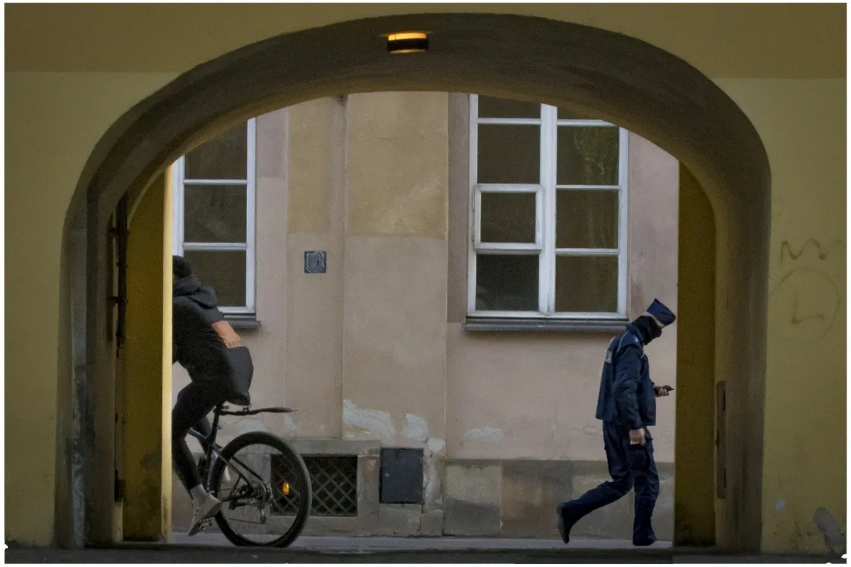 Cyclist and pedestrian passing through a yellow archway